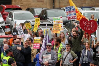 Counter protesters can be seen by keeping signs of 'Welcome to Refugees'